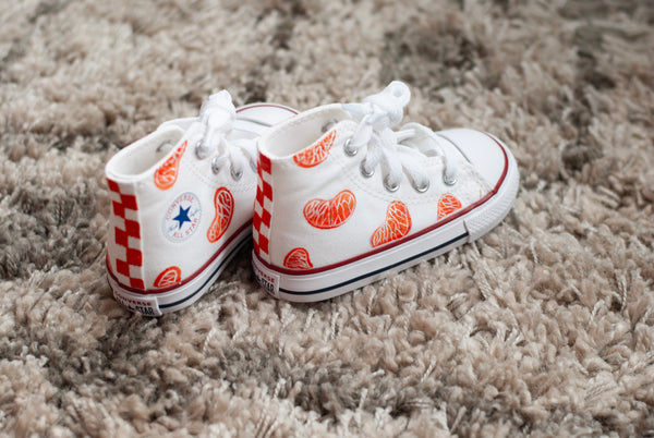white high top converse with orange slices painted on with an orange checkered back.