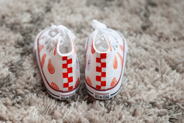 white high top converse with orange slices painted on with an orange checkered back.