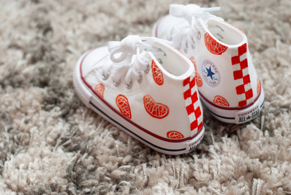 white high top converse with orange slices painted on with an orange checkered back.