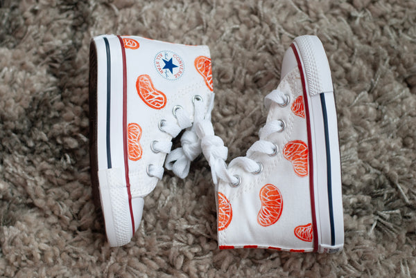 white high top converse with orange slices painted on with an orange checkered back.