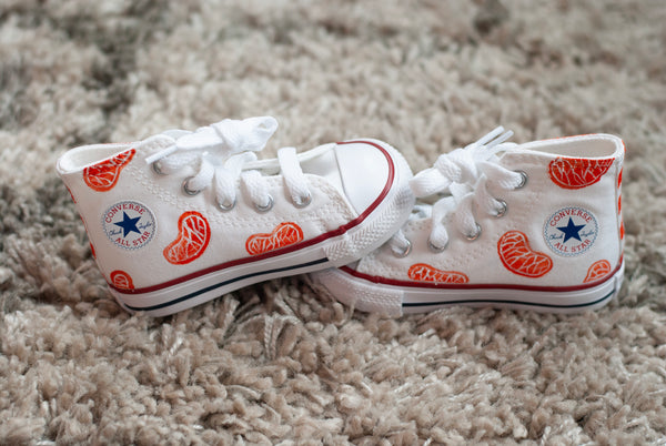 white high top converse with orange slices painted on with an orange checkered back.