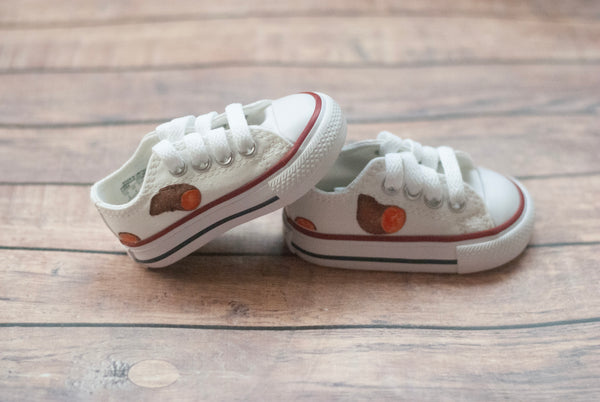 White low top converse with sweet potatoes painted on the sides. 
