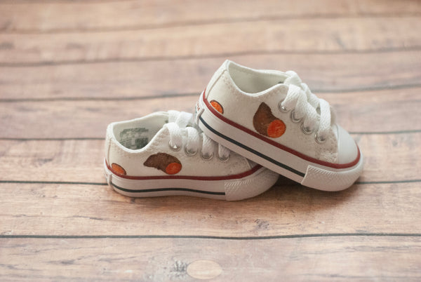 White low top converse with sweet potatoes painted on the sides. 