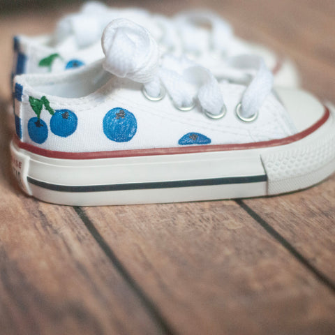 White sneakers with blueberry design on a wooden floor