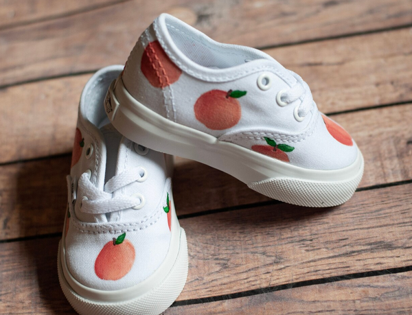 White tie vans with hand painted peaches scattered along the sides. 