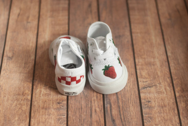 White toddler vans sneakers with strawberry and checkered design on a wooden floor