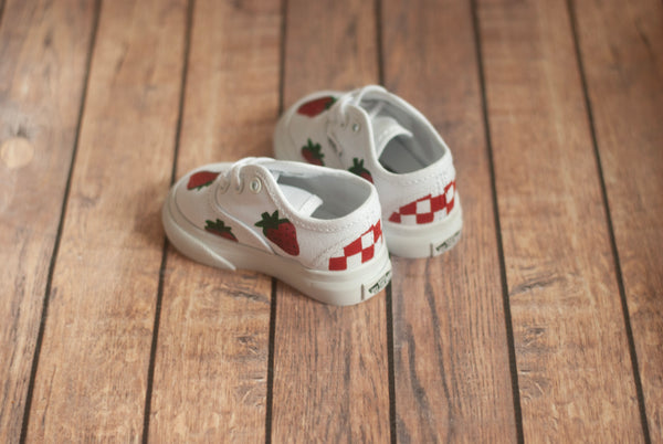 White vans sneakers with strawberry and checkered pattern on a wooden floor