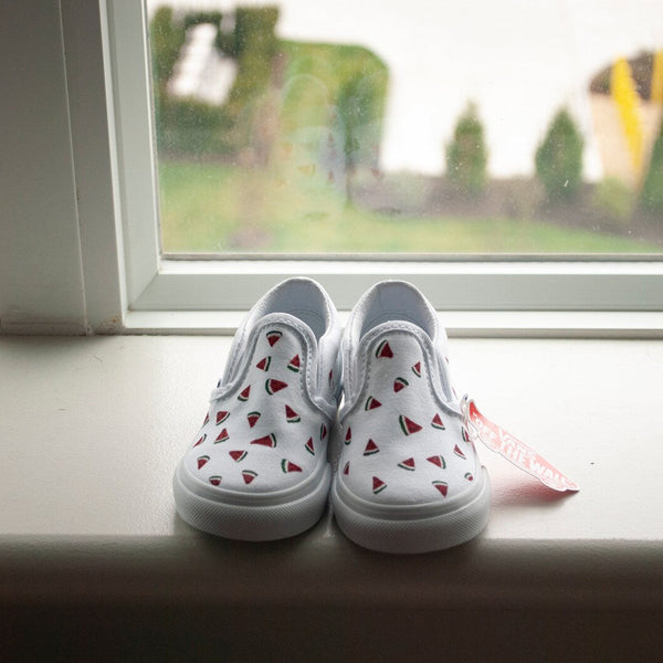 watermelon slices hand painted on slip on vans in front of a window. 